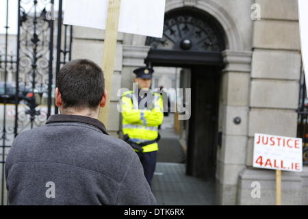 Dublin, Irland. 19. Februar 2014. Demonstrant steht außerhalb der Fußgänger-Eingang Dail (Irisches Parlament) mit einem Garda Offizier (irischer Polizist) bewachen den Eingang. Protest in Dublin forderte den Rücktritt der Justiz Minister Alan Shatter und Kommissar Martin Callinan nach angeblichen Mobbing von Garda (irische Polizei) Informanten Maurice McCabe und John Wilson und andere angebliche Korruption in die Gardai. Bildnachweis: Michael Debets/Alamy Live-Nachrichten Stockfoto