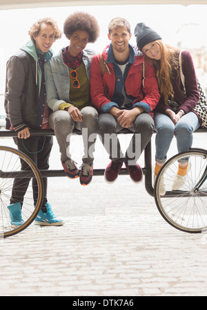 Freunde, die zusammen auf städtischen Fahrradträger lächelnd Stockfoto