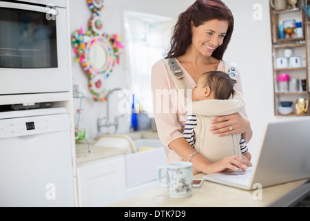 Mutter mit jungen und mit Laptop in der heimischen Küche