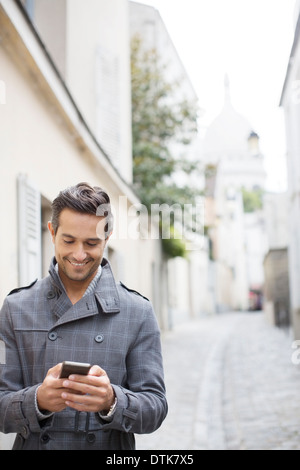 Geschäftsmann mit Handy auf Stadtstraße in der Nähe von Sacre Coeur Basilika, Paris, Frankreich Stockfoto