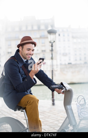 Geschäftsmann mit Handy auf dem Fahrrad entlang Seine, Paris, Frankreich Stockfoto