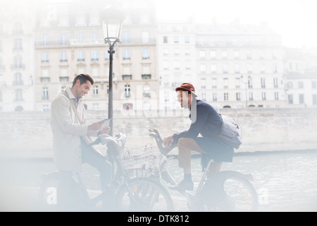 Geschäftsleute sprechen auf Fahrrädern entlang Seine, Paris, Frankreich Stockfoto