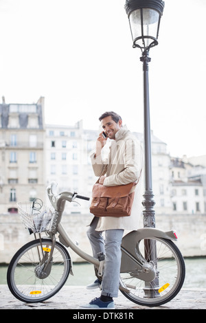 Geschäftsmann, reden über Handy auf dem Fahrrad entlang Seine, Paris, Frankreich Stockfoto
