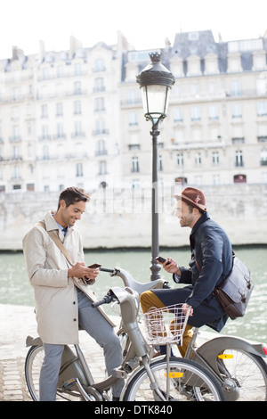 Unternehmer mit dem Handy auf dem Fahrrad entlang Seine, Paris, Frankreich Stockfoto