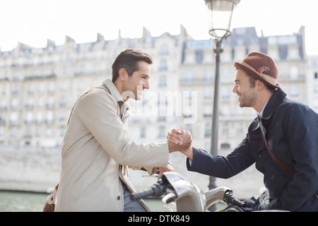 Geschäftsleute Händeschütteln auf Fahrrädern entlang Seine, Paris, Frankreich Stockfoto