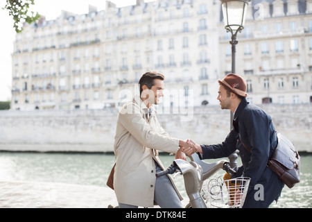 Geschäftsleute Händeschütteln auf Fahrrädern entlang Seine, Paris, Frankreich Stockfoto