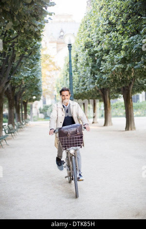 Geschäftsmann Reiten Fahrrad im Park, Paris, Frankreich Stockfoto