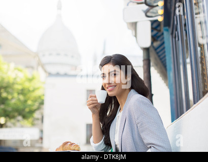 Frau trinkt Espresso im Straßencafé in der Nähe von Sacre Coeur Basilika, Paris, Frankreich Stockfoto