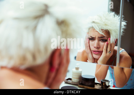 Verkatert Frau prüft sich selbst im Spiegel Stockfoto