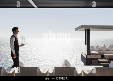 Kellner servieren Champagner im Cabana mit Blick auf Meer Stockfoto