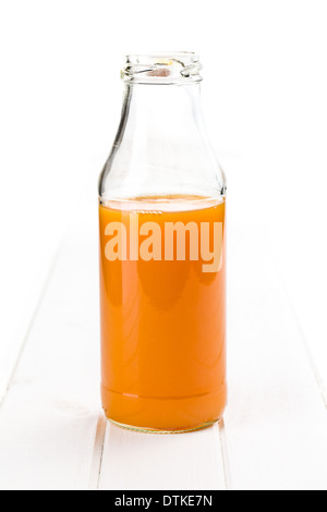 Flasche Karottensaft auf weißem Holz Hintergrund Stockfoto
