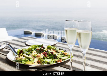 Teller mit Salat und Gläser Champagner auf Tisch im freien Stockfoto