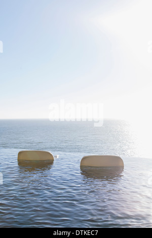 Gartenmöbel im Infinity-Pool mit Blick auf Meer Stockfoto