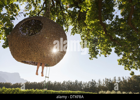 Frau baumelnden Füße von Nest Baumhaus Stockfoto