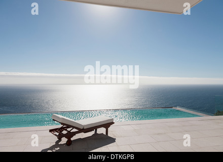 Lounge-Sessel und Infinity-Pool mit Blick auf Meer Stockfoto