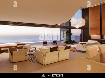 Wohnzimmer im modernen Haus mit Blick auf Meer bei Sonnenuntergang Stockfoto