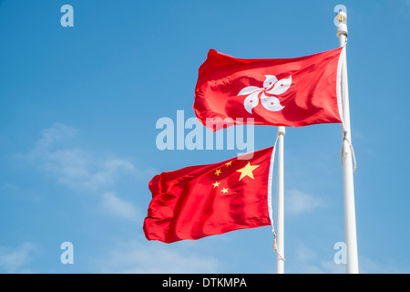 Flaggen von China und Hong Kong fliegen auf Fahnenmasten. Stockfoto