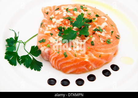 Mariniertes Lachsfilet mit Olivenöl, Petersilie, Knoblauch auf Platte Stockfoto