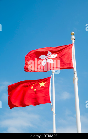 Flaggen von China und Hong Kong fliegen auf Fahnenmasten. Stockfoto