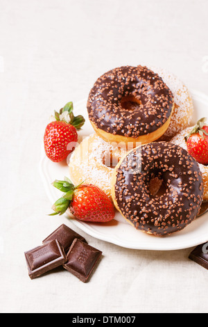 Platte mit Schokoladen Donuts, frischen Erdbeeren und dunkle Schokolade serviert auf grau Textil. Serien ansehen Stockfoto