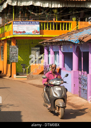 Indien, Goa, Chapora, Mann ohne Helm fahren Motorroller durch Dorf Stockfoto