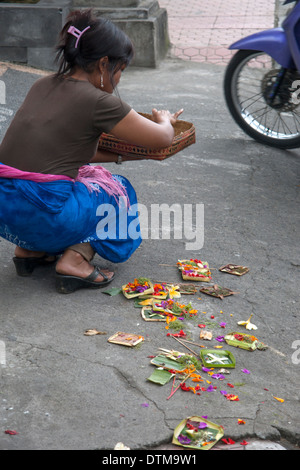 Eine asiatische Frau, die ihre Opfergaben auf dem Bürgersteig in Ubud, Bali, Indonesien Stockfoto