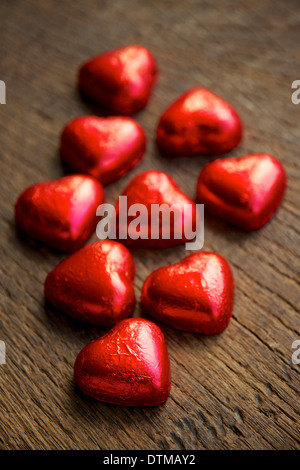 Rote Folie eingewickelt Schokoladenherzen. Stockfoto