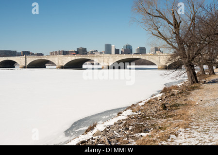 WASHINGTON DC, USA - Arlington Memorial Bridge überspannt eine Fläche von Eis und Schnee - Potomac von Washington D.C. in Arlington, Virginia, mit den Gebäuden von Rosslyn in der Ferne sichtbar. Die Potomac in Washington DC ausgeführt wird eingefroren und mit einer Schicht von Schnee bedeckt. Die Region hat einen ungewöhnlich kalten Winter erlebt, mit anhaltend niedrigen Temperaturen. Stockfoto