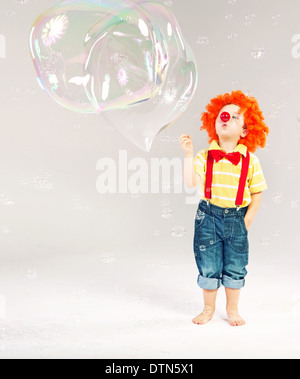 Lustiges Bild des kleinen Clowns machen riesige Seifenblasen Stockfoto