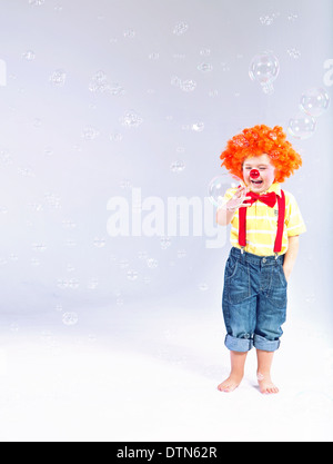 Lustiges Bild des kleinen Clowns machen große Seifenblasen Stockfoto