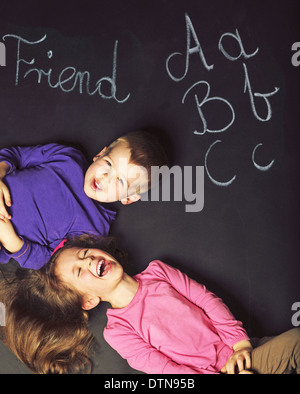 Niedliche Kinder spielen auf dem schwarzen Brett Stockfoto