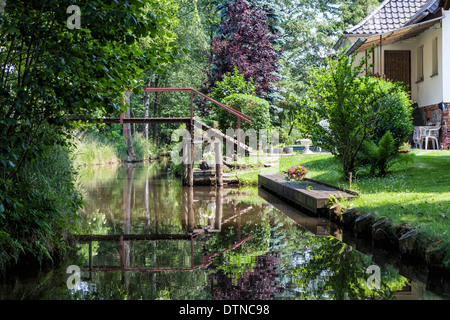 Haus mit Fußgängerbrücke am Ufer des Bewässerungskanals im Spreewald Biosphärenreservat, Brandenburg, Deutschland Stockfoto