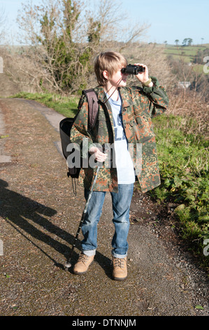 Junge vogel Spotter in einem Camouflage Jacke hält ein paar alte Fernglas und schaut, obwohl Sie im hellen Sonnenschein Stockfoto