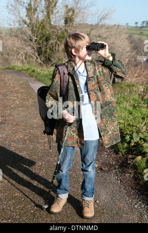 Junge vogel Spotter in einem Camouflage Jacke hält ein paar alte Fernglas und schaut, obwohl Sie im hellen Sonnenschein Stockfoto