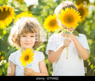 Glückliche Kinder, die spielen mit Sonnenblumen Stockfoto