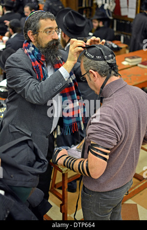 LUBAWITSCH OUTREACH.  Ein orthodoxen religiösen jüdischen Mann hilft, die ein nicht-religiösen Juden auf Gebetsriemen für das Morgengebet zu setzen. NEW YORK CITY Stockfoto