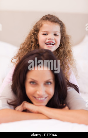 Mädchen sitzen auf dem Rücken der Mütter Stockfoto