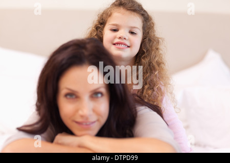 Lächelndes Mädchen sitzen auf ihr Mütter zurück Stockfoto