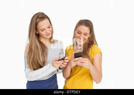 Zwei junge Frauen SMS auf ihren Handys Stockfoto