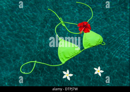 Schwimmen im Pool mit Plumeria Blumen und einen Hibiskus grünen Bikini-Oberteil Stockfoto