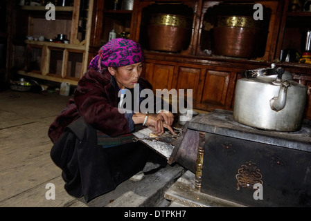 Tibetische Frau Kochen auf einem Holzofen im Tsum Valley, Nepal. Stockfoto