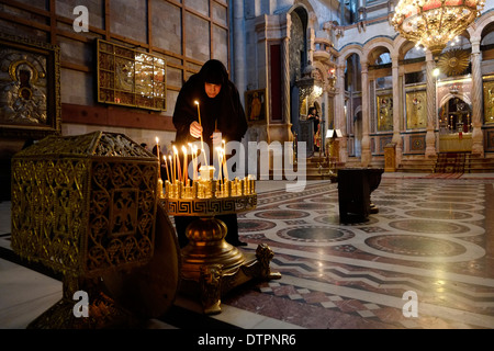 Ein christlich-orthodoxer Gläubiger zündet während einer Massenprozession über den Omphalos im griechisch-orthodoxen Katholikon oder der Katholikon-Kapelle in der Grabeskirche in der Altstadt von Jerusalem Israel Kerzen an Stockfoto