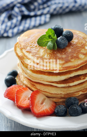 Pfannkuchen mit frischen Beeren, Minze und Ahornsirup auf weißen Teller closeup Stockfoto