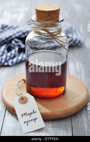 Ahornsirup in Glasflasche auf einem hölzernen Hintergrund Stockfoto