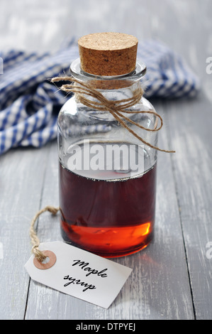 Ahornsirup in Glasflasche auf einem hölzernen Hintergrund Stockfoto