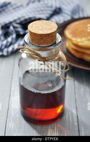 Ahornsirup in Glasflasche auf einem hölzernen Hintergrund Stockfoto