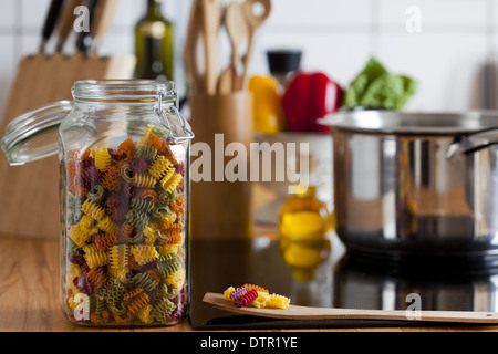 Lagerung Jar mit bunten Nudeln und Kochen Löffel auf Arbeitsplatte mit textfreiraum am rechten Bildbereich Stockfoto