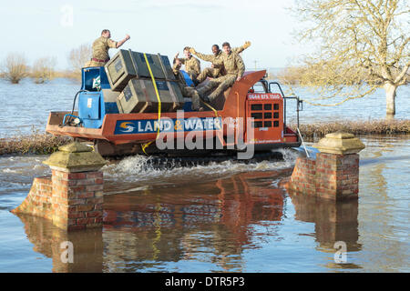 Burrowbridge, UK. 22. Februar 2014. Kommandos helfen bei Burrowbridge auf den überfluteten Somerset Niveaus am 22. Februar 2014. Eine Gruppe von Soldaten winken für die Kamera, wie sie durch das Hochwasser von Mitarbeitern der Umweltagentur in Trac-Dumper, einem spezialisierten Fahrzeug gehen durch tiefes Wasser transportiert werden. Versorgung mit Erdöl und mechanischen Teile werden an Saltmoor Pumping Station geschickt wo Wasser aus Northmoor in den Gezeiten-Fluß Parrett zu entlasten, das überschwemmte Gebiet gepumpt wird. Das sind die schlimmsten Überschwemmungen auf der Somerset Levels in lebendige Geschichte. Stockfoto