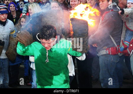 Ein Junge trägt einen brennenden Teer Lauf auf seinen Schultern. Stockfoto