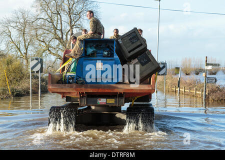 Burrowbridge, UK. 22. Februar 2014. Kommandos helfen bei Burrowbridge auf den überfluteten Somerset Niveaus am 22. Februar 2014. Eine Gruppe von Soldaten sind durch das Hochwasser von Arbeitern der Umweltagentur in Trac-Dumper, einem spezialisierten Fahrzeug gehen durch tiefes Wasser transportiert. Versorgung mit Erdöl und mechanischen Teile werden an Saltmoor Pumping Station geschickt wo Wasser aus Northmoor in den Gezeiten-Fluß Parrett zu entlasten, das überschwemmte Gebiet gepumpt wird. Das sind die schlimmsten Überschwemmungen auf der Somerset Levels in lebendige Geschichte. Stockfoto